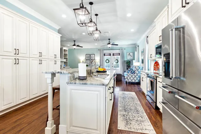 a kitchen with stainless steel appliances granite countertop a stove top oven a sink a dining table and chairs with wooden floor