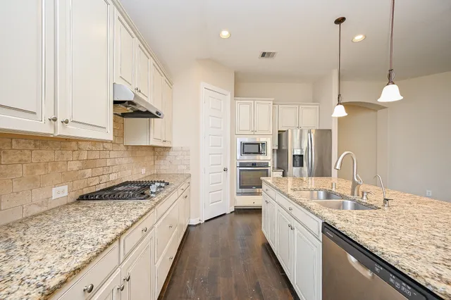 a large kitchen with kitchen island granite countertop a sink a counter space appliances and cabinets
