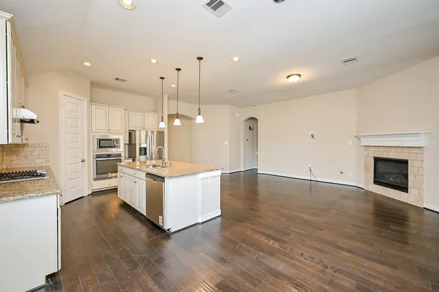 a large white kitchen with wooden floors and stainless steel appliances