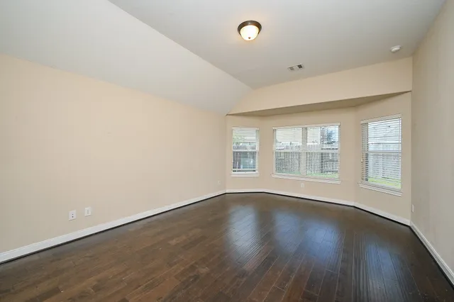 an empty room with wooden floor and windows
