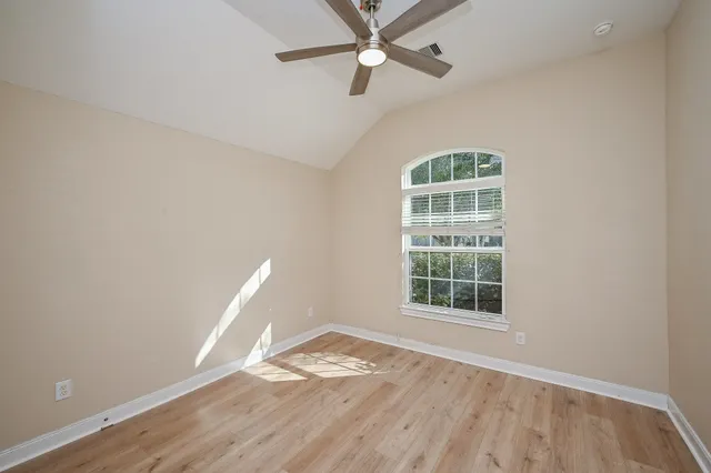 an empty room with wooden floor cabinet and windows
