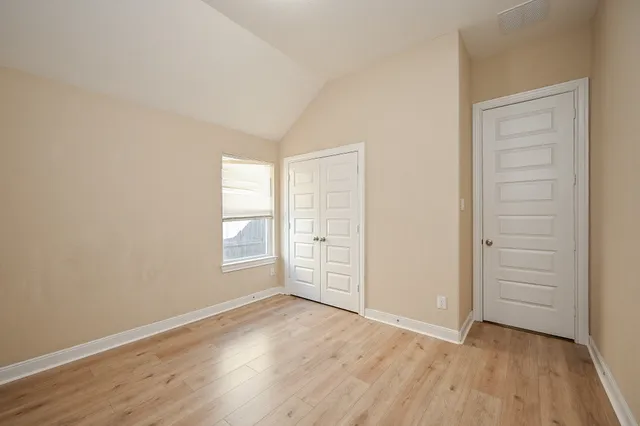 an empty room with wooden floor cabinet and windows