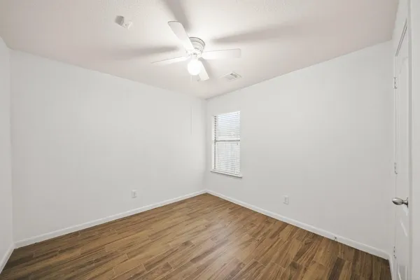 an empty room with wooden floor and fan