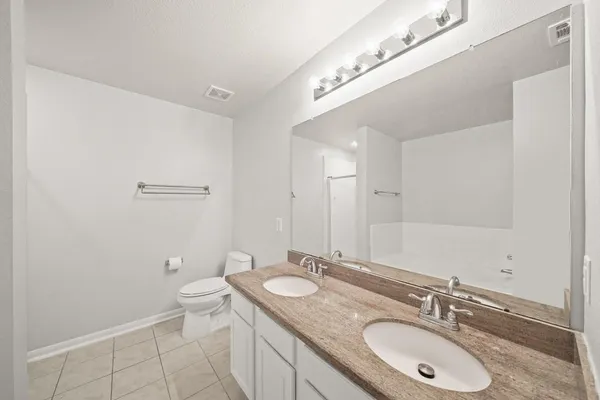 a bathroom with a granite countertop sink a toilet and a mirror