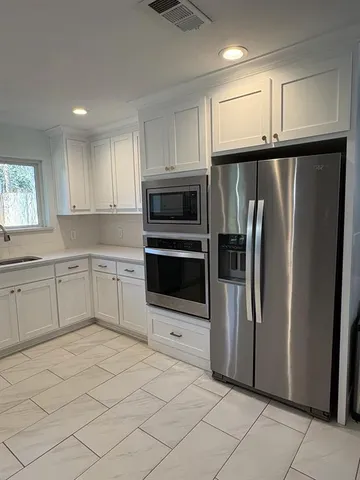a kitchen with stainless steel appliances a refrigerator sink and microwave