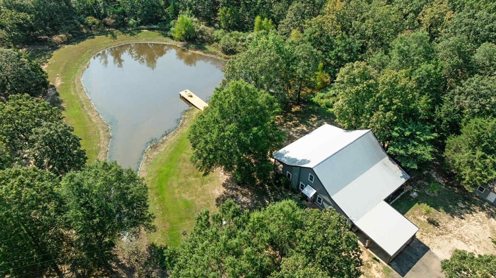 an aerial view of a house with a yard and trees all around