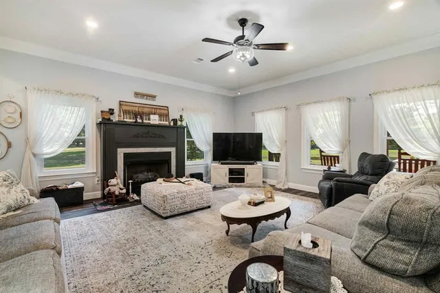 a living room with furniture a fireplace a flat screen tv and a large window