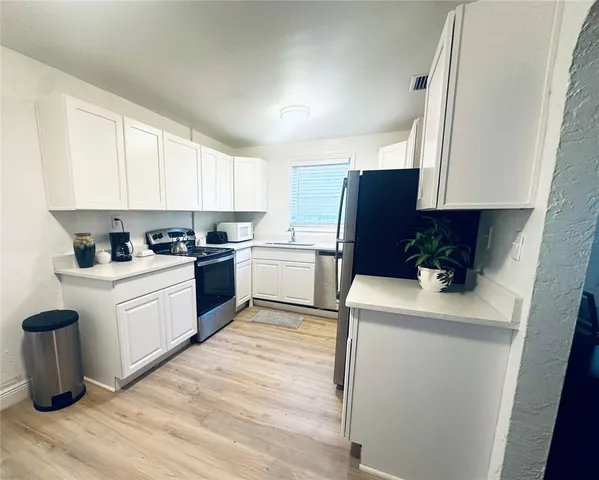 a kitchen with a refrigerator sink and white cabinets