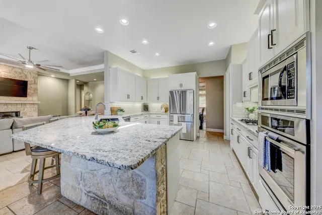 a kitchen with granite countertop white cabinets and white appliances