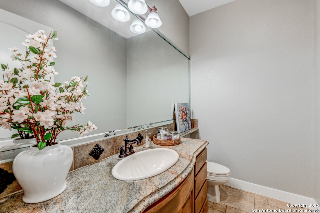 142 Candelaria Helotes, TX 78023 - Photo 19 of 53 a bathroom with a granite countertop sink and a mirror with toilet