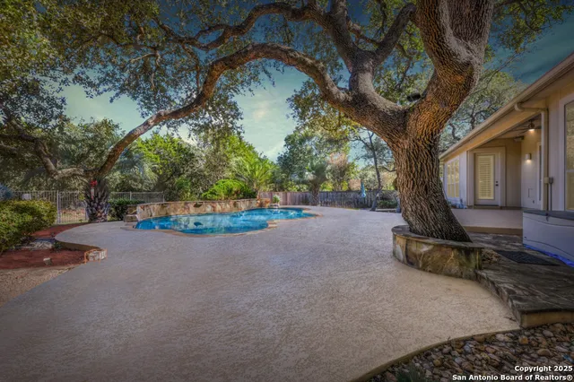 a view of a swimming pool with a patio and trees