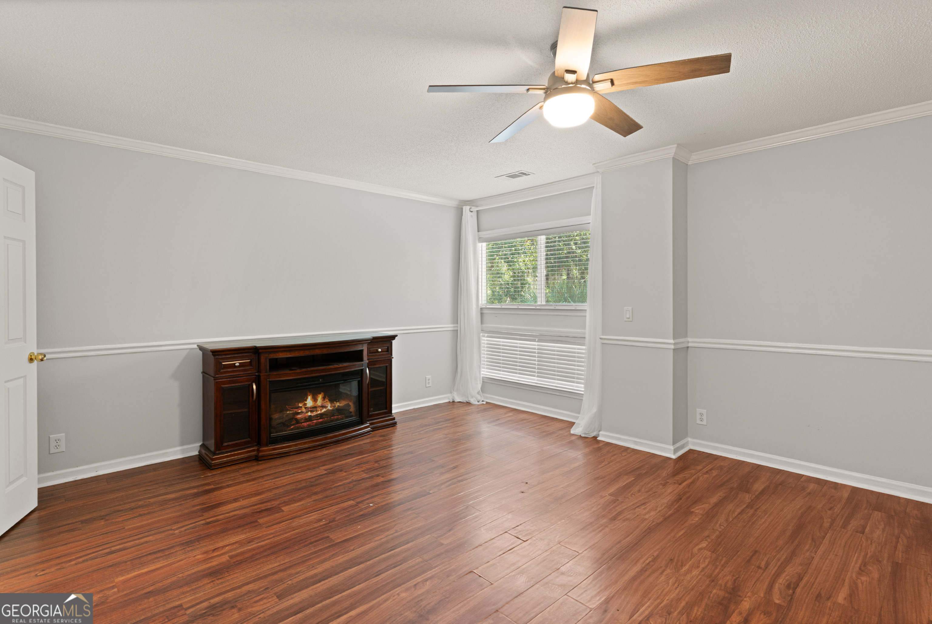 1000 Mallery St Extension, Unit B5 St. Simons, GA 31522 - Photo 16 of 24 a view of an empty room with wooden floor fireplace and a window
