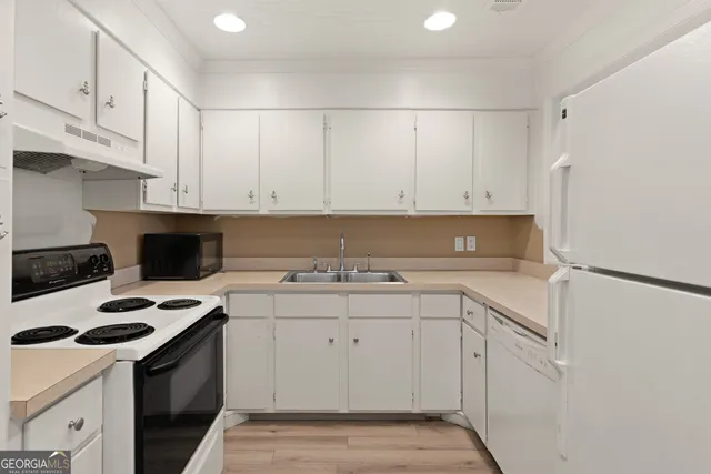 a kitchen with a sink a stove and white cabinets
