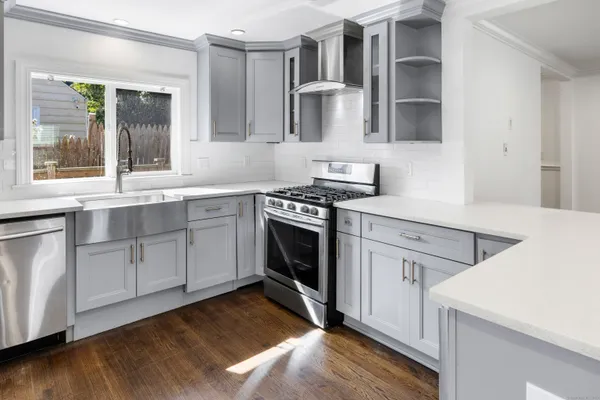 a kitchen with a stove white cabinetry and wooden floor