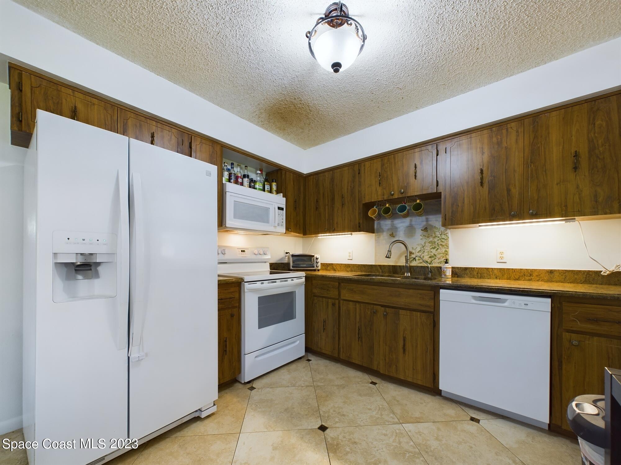 344 Columbus Street Sebastian, FL 32958 - Photo 16 of 35 a kitchen with stainless steel appliances granite countertop a refrigerator a sink dishwasher a stove with wooden cabinets