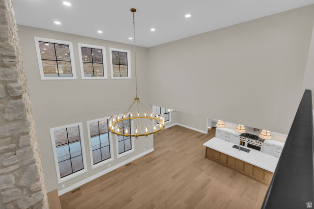 2828 Jojo Road Eagle Mountain, UT 84005 - Photo 38 of 63 Vaulted living space with a brass chandelier, upper and lower transom windows, a stone-clad column, and wide plank wood-finish flooring