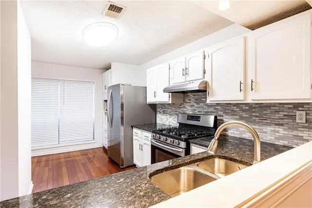 a kitchen with granite countertop a sink stainless steel appliances and cabinets