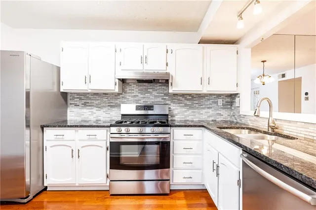 a kitchen with stainless steel appliances granite countertop a sink stove and refrigerator