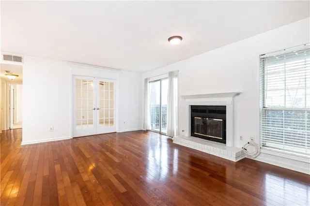 an empty room with wooden floor fireplace and windows