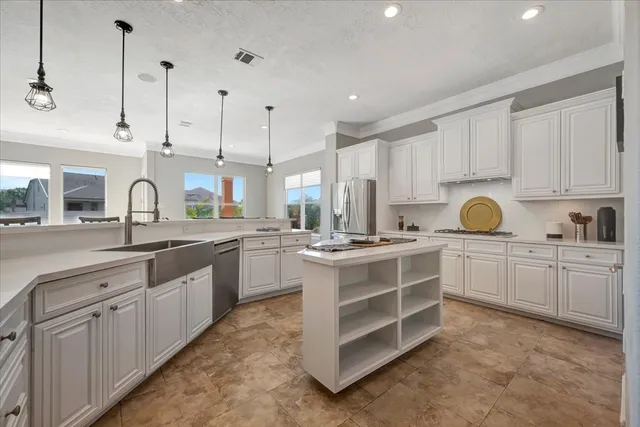 a kitchen with kitchen island granite countertop a stove a sink and white cabinets