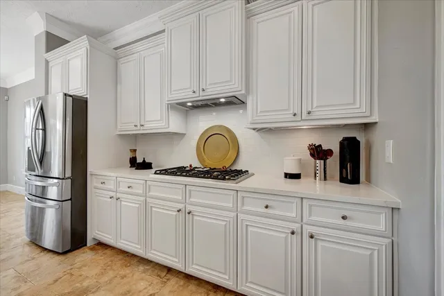 a kitchen with stainless steel appliances granite countertop a refrigerator a stove a sink and white cabinets