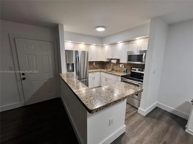 a kitchen with stainless steel appliances granite countertop a sink and a refrigerator