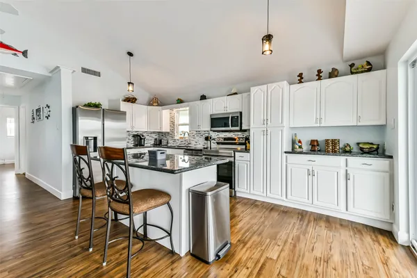 a kitchen with stainless steel appliances granite countertop wooden floors a refrigerator and cabinets