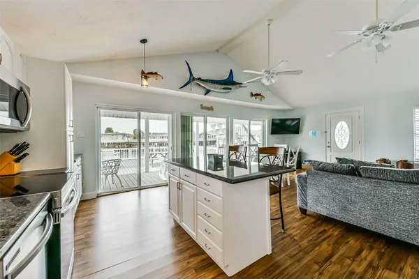 a living room with stainless steel appliances granite countertop furniture and wooden floors