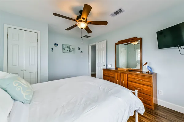 a bedroom with a large bed a flat tv screen and a dresser