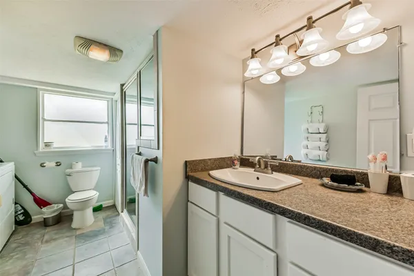 a bathroom with a granite countertop sink a toilet and a mirror
