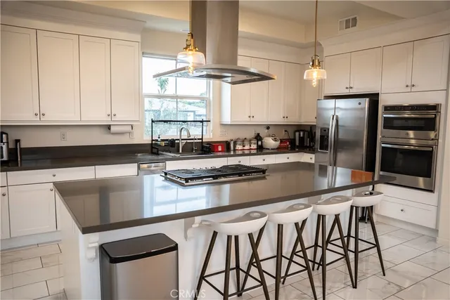 a kitchen with stainless steel appliances granite countertop a sink a stove a refrigerator cabinets and a dining table