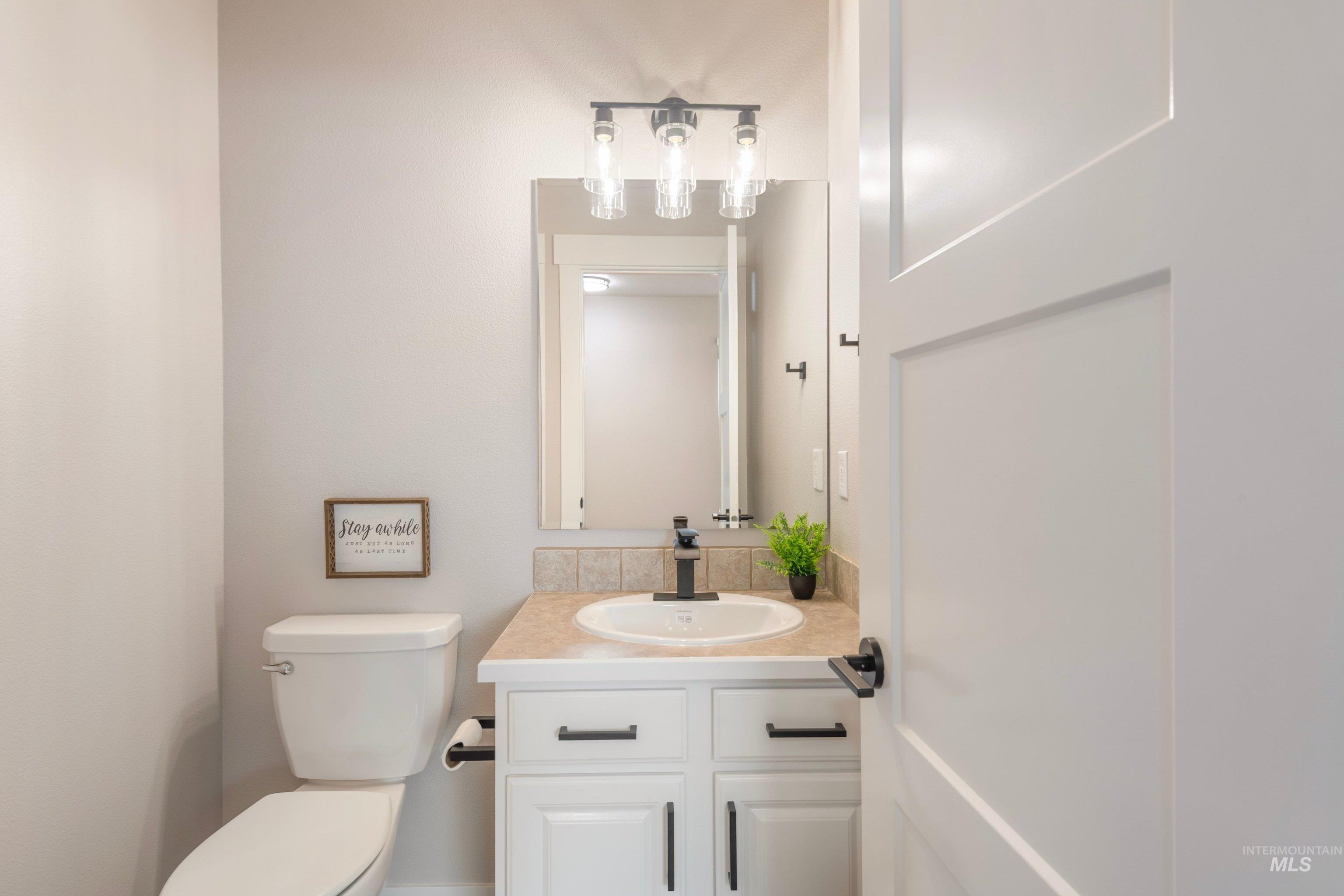 16759 Abram Avenue Caldwell, ID 83607 - Photo 15 of 33 Modern bathroom featuring a white vanity with black hardware, a rectangular vanity mirror, and a three-light vanity fixture