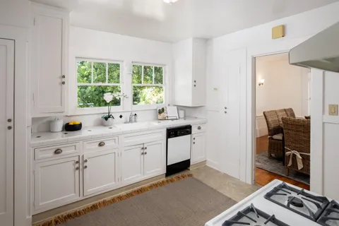 a kitchen with white cabinets a sink and a window