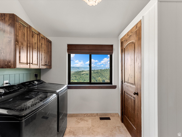 1225 Old Oregon Road Soda Springs, ID 83276 - Photo 18 of 67 Functional laundry area featuring dark wood-finish cabinetry, a window with mountain and forest scenery, tile flooring, and a wood-finish interior door