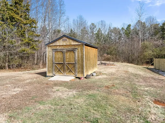 a view of wooden house with a yard and covered with snow in front of house