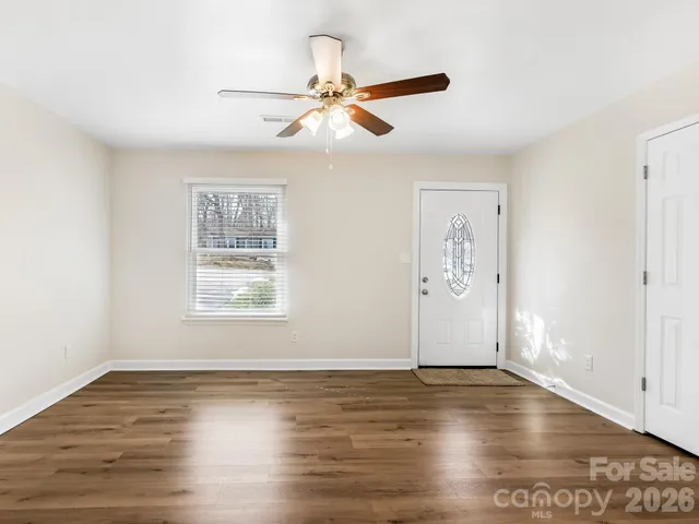 an empty room with wooden floor fan and windows