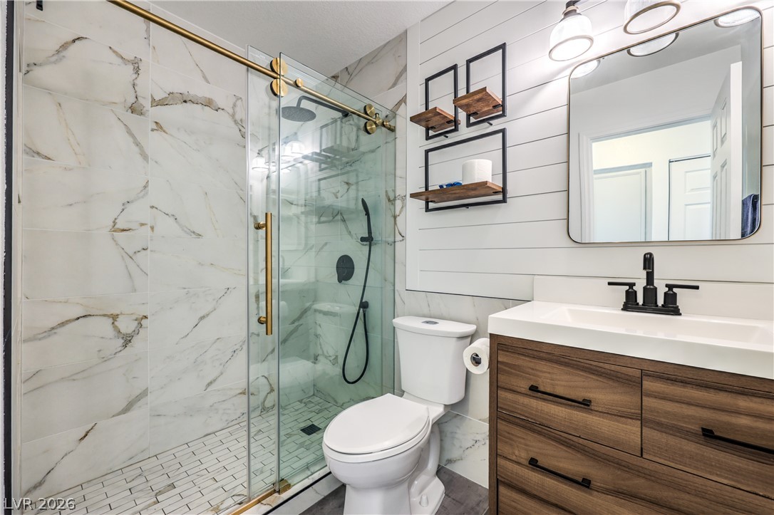 1900 Cardinal Point Street Henderson, NV 89012 - Photo 24 of 32 A well-appointed bathroom features a glass-enclosed shower, a sleek vanity, and decorative wall shelving.