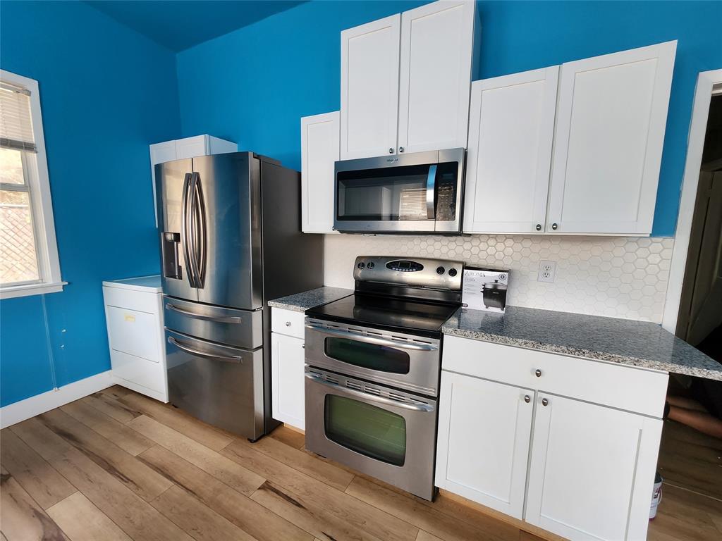 511 West Sycamore Street, Unit A Denton, TX 76201 - Photo 1 of 10 Kitchen with backsplash, appliances with stainless steel finishes, white cabinets, and light wood-type flooring