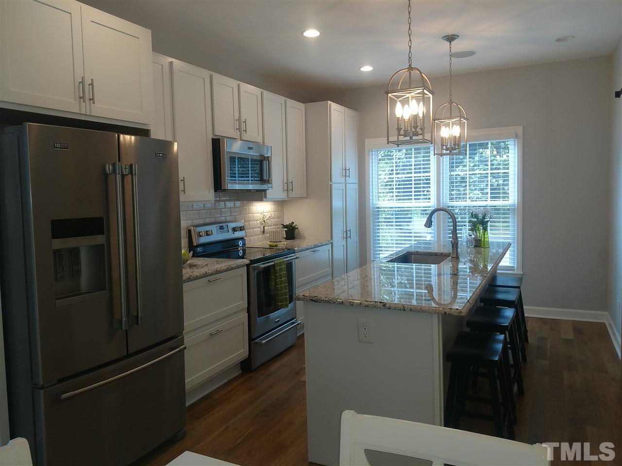 12101 Amoretto Way Raleigh, NC 27613 - Photo 3 of 15 a kitchen with stainless steel appliances granite countertop a refrigerator a stove a sink a microwave and island