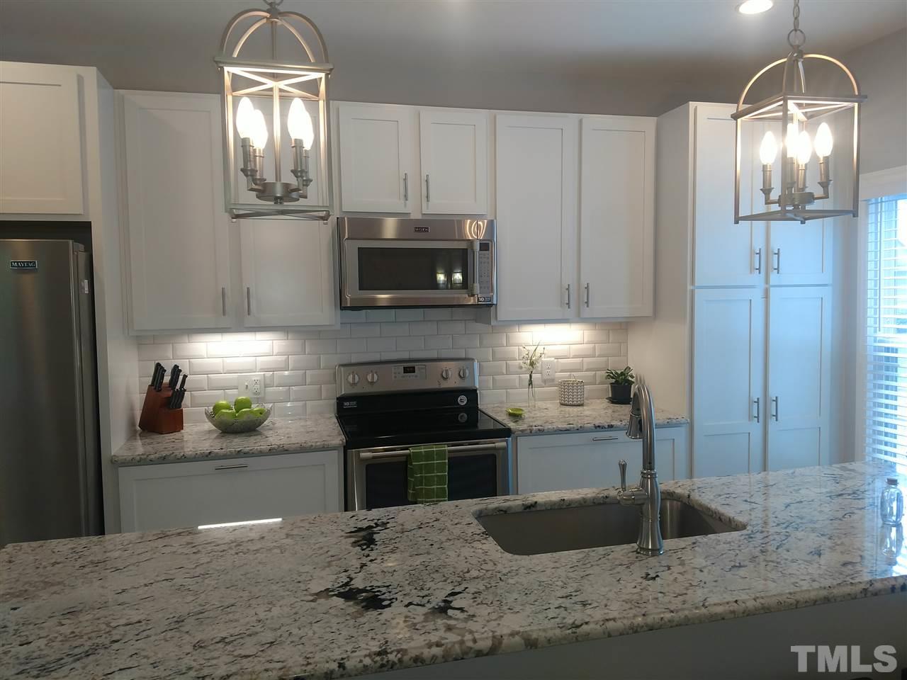 12101 Amoretto Way Raleigh, NC 27613 - Photo 4 of 15 a kitchen with kitchen island granite countertop a stove and a sink
