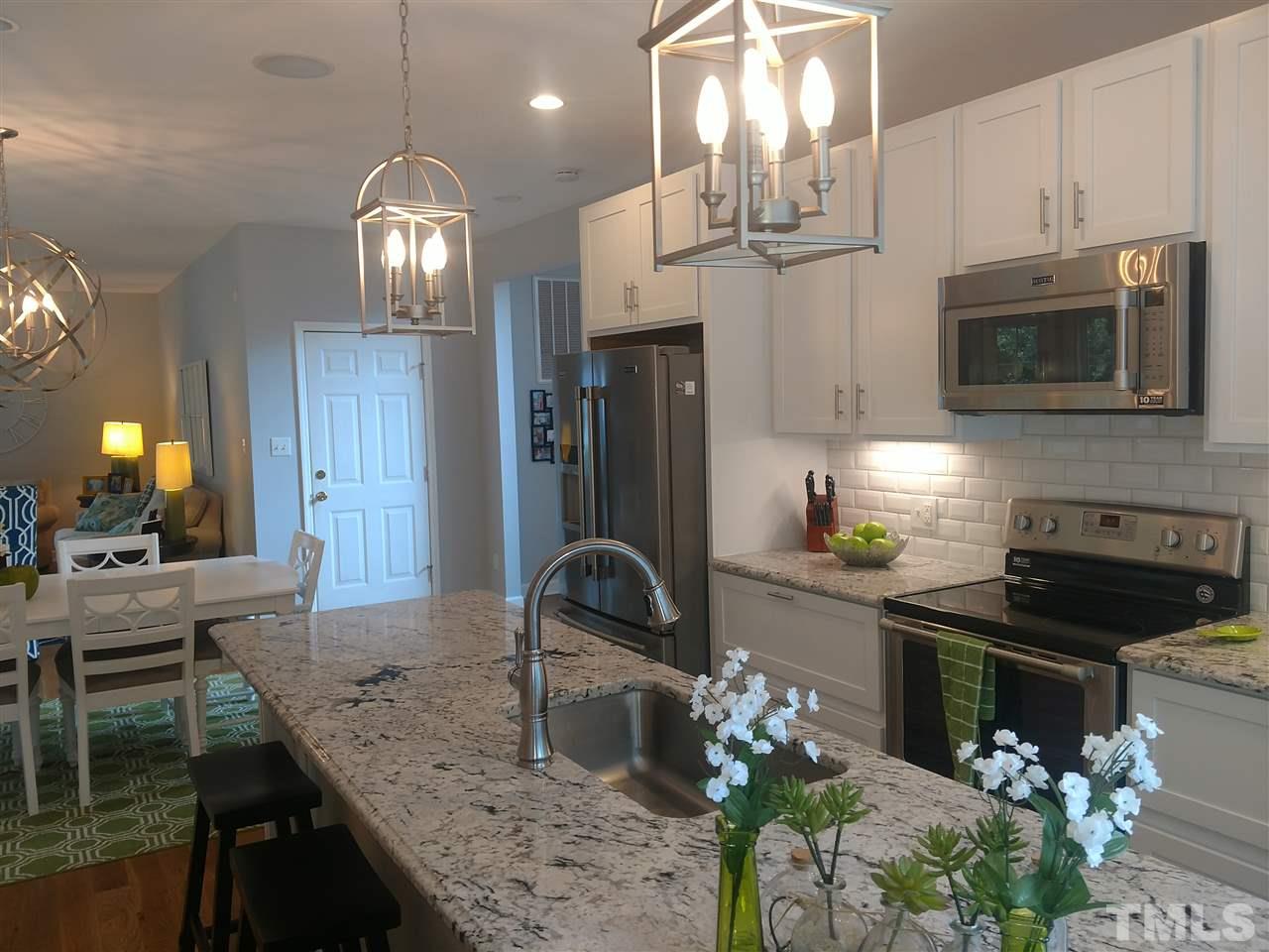 12101 Amoretto Way Raleigh, NC 27613 - Photo 5 of 15 a kitchen with stainless steel appliances granite countertop a stove refrigerator and cabinets