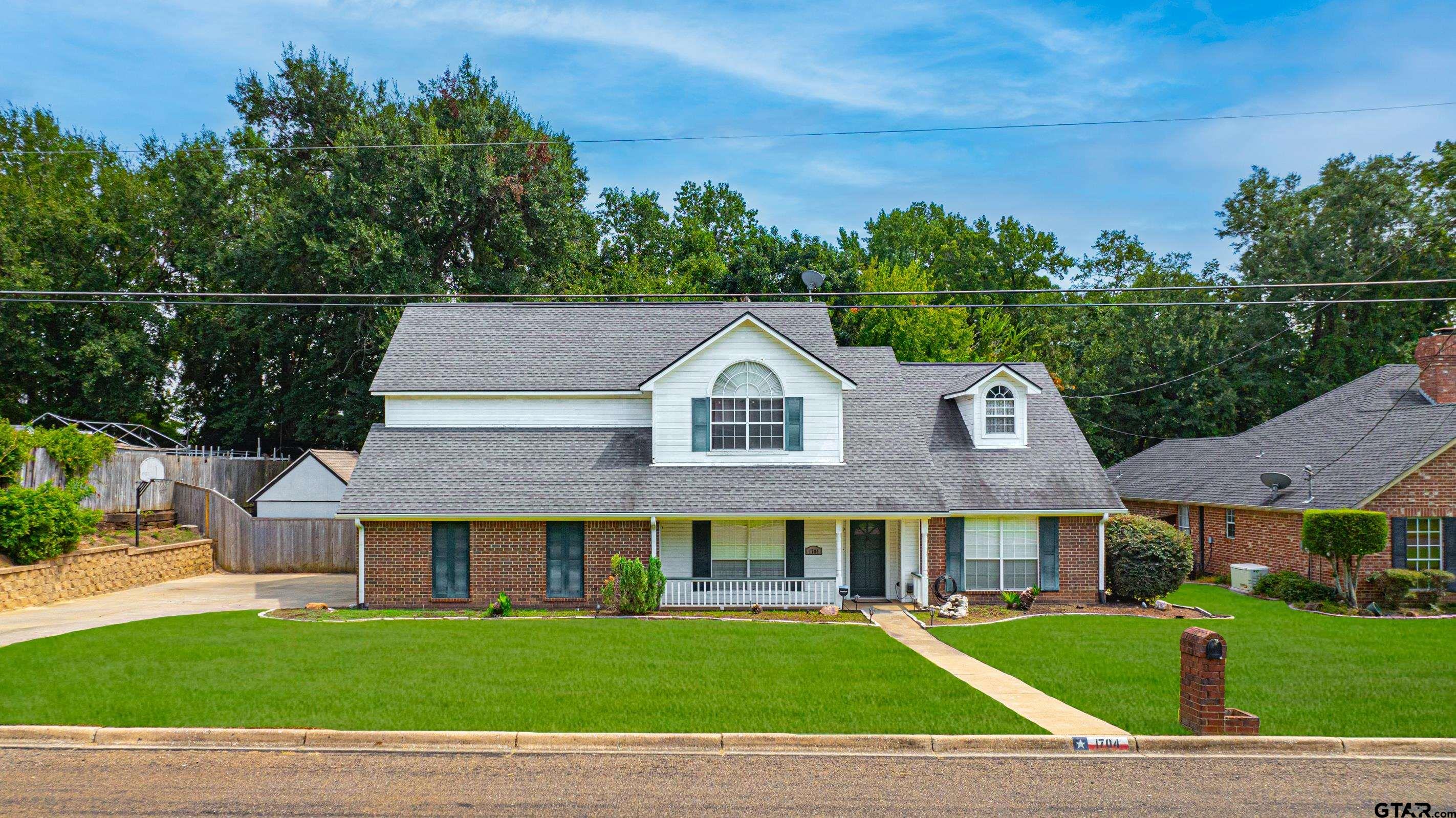 a view of a big house with a big yard and large trees