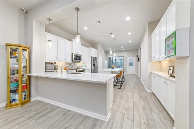 a kitchen with stainless steel appliances a refrigerator a sink dishwasher a stove and white cabinets with wooden floor