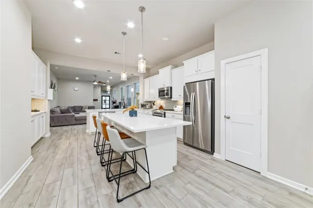 a kitchen with stainless steel appliances a refrigerator a stove a sink dishwasher and a dining table with wooden floor