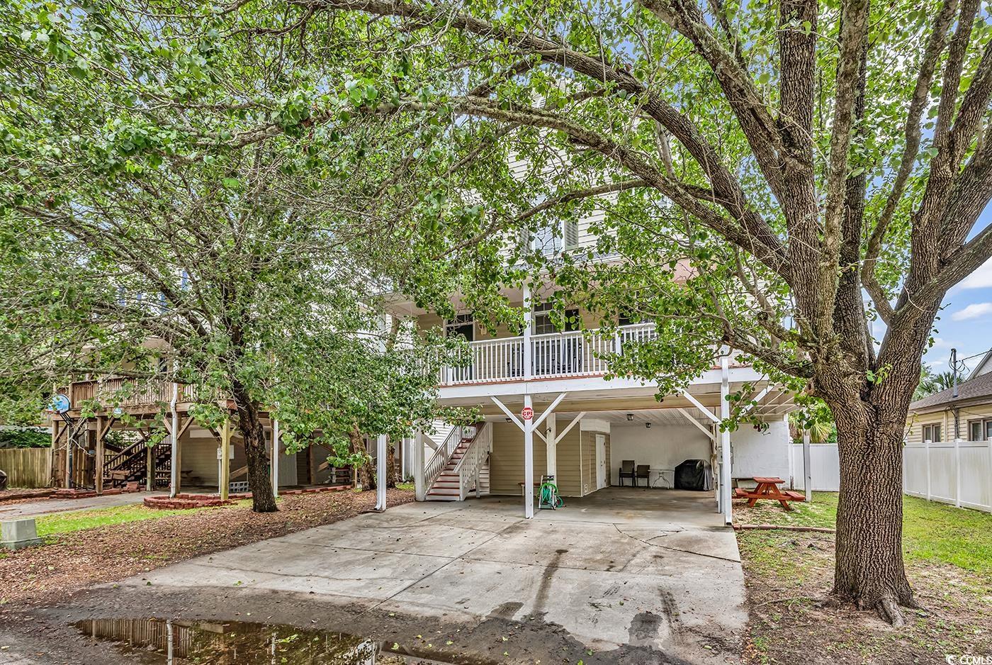 View of front of house featuring stairs, a carport, driveway, and fence