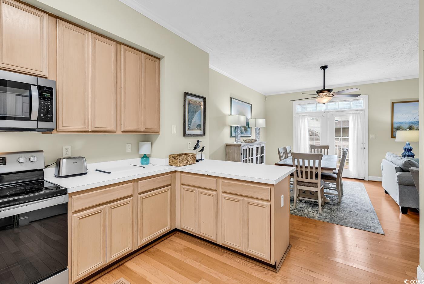 17 South Oak Drive Surfside Beach, SC 29575 - Photo 5 of 38 Kitchen with stainless steel appliances, light brown cabinets, crown molding, a peninsula, and light wood-type flooring