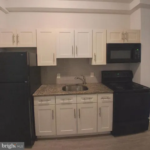 a kitchen with granite countertop a sink dishwasher a stove and a microwave oven