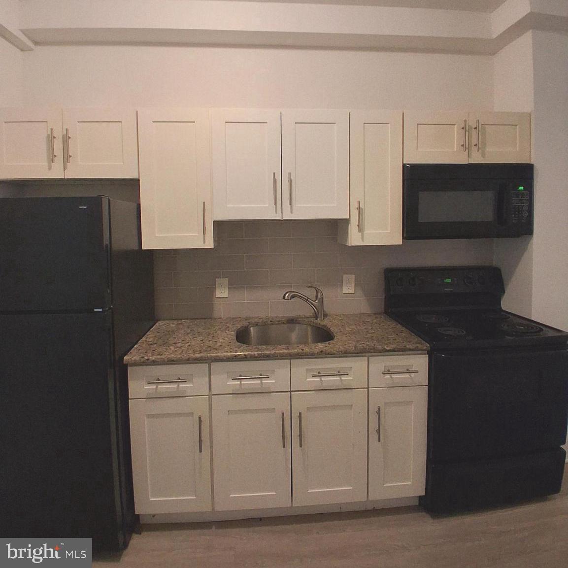 6104 Market Street, Unit 2 Philadelphia, PA 19139 - Photo 3 of 11 a kitchen with granite countertop a sink dishwasher a stove and a microwave oven