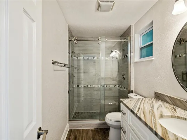 a bathroom with a granite countertop sink toilet mirror and shower