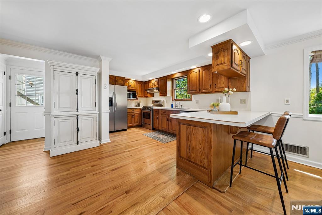 99 Ferncliff Road Bloomfield, NJ 07003 - Photo 12 of 30 a kitchen with stainless steel appliances kitchen island granite countertop a refrigerator a stove a sink with island chairs and wooden floor